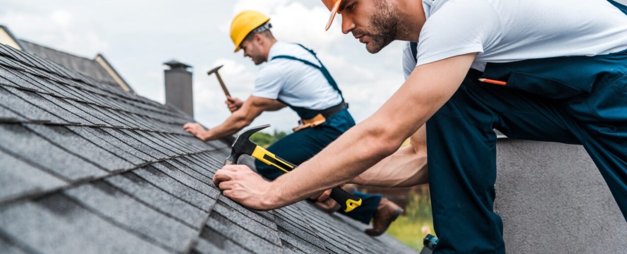 selective focus of handsome handyman repairing roof with coworker